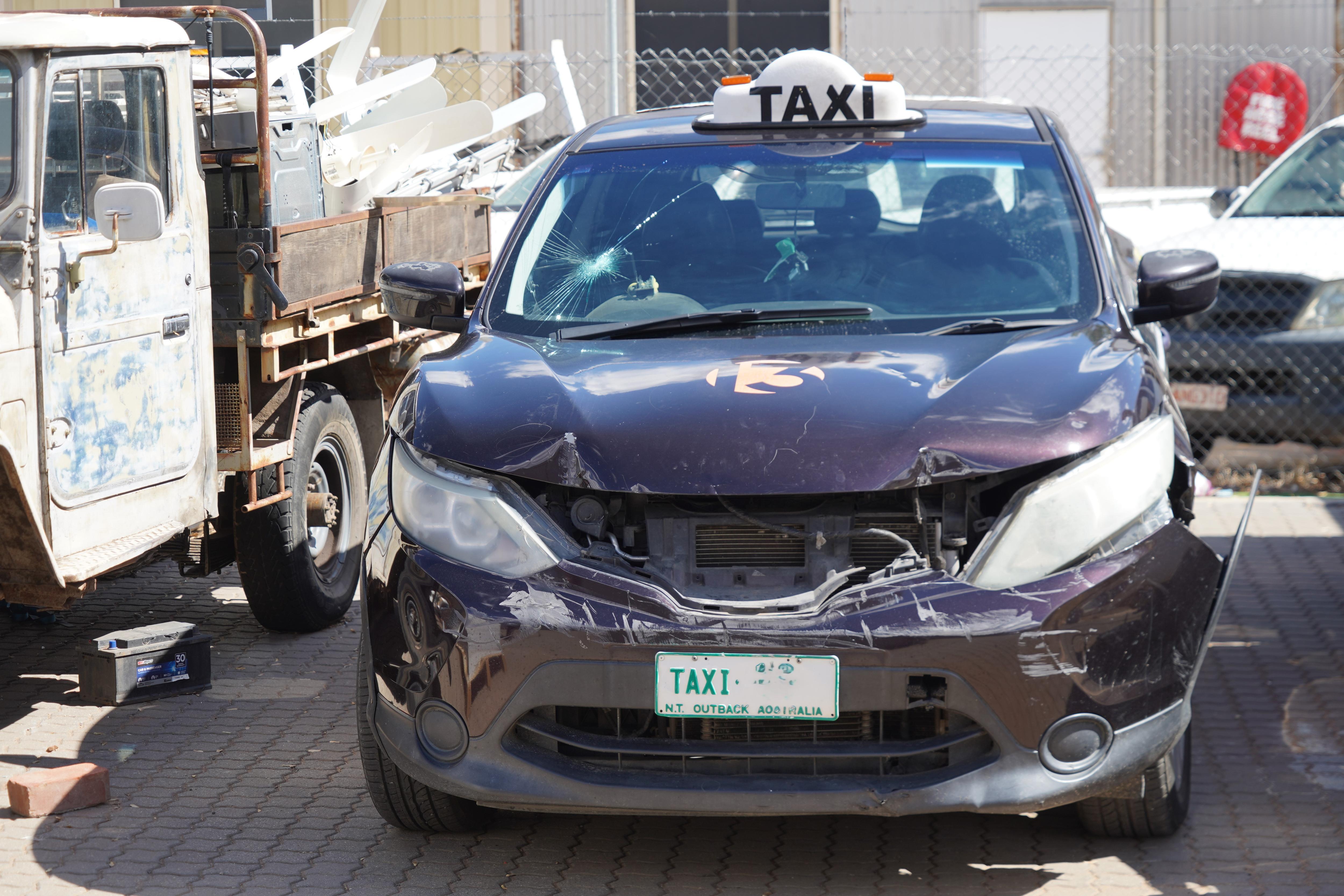 A black taxi without its front bumper and other damage