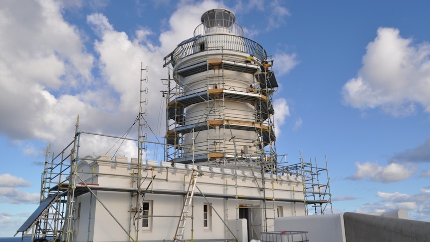 A lighthouse on an island surrounded by scaffolding for renovation work