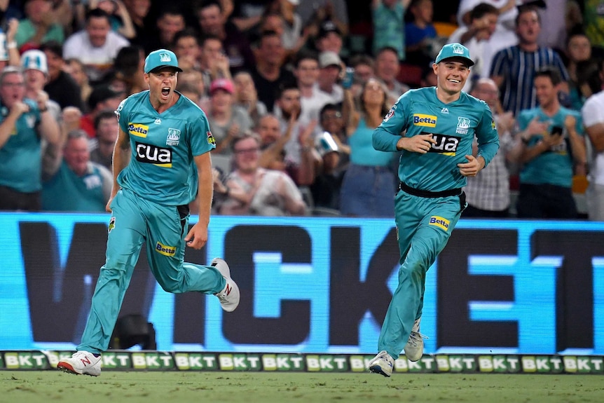 Ben Laughlin (left) runs as he celebrates taking a catch against the Strikers in the BBL.