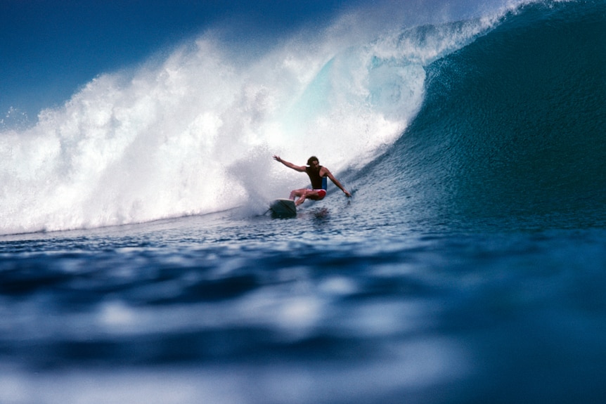 An old photo shows a surfer riding a wave.