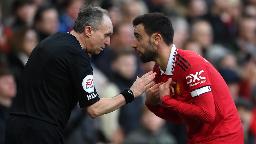 Manchester United's Bruno Fernandes points to his chest as he speaks to the assistant referee during a Premier League game.
