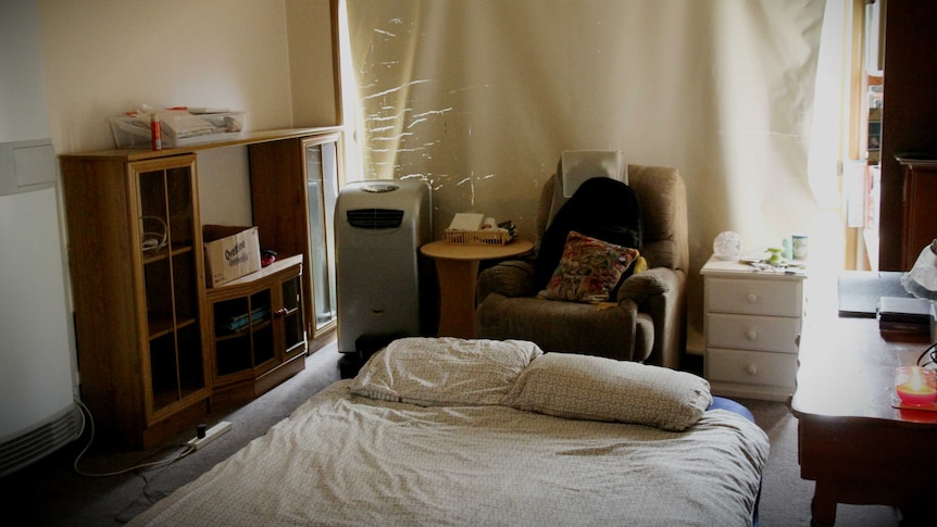 A blow-up mattress is in the middle of the living room floor, the bed is made.