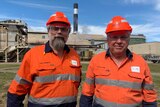 two men in hi vis in front of a sugar mill
