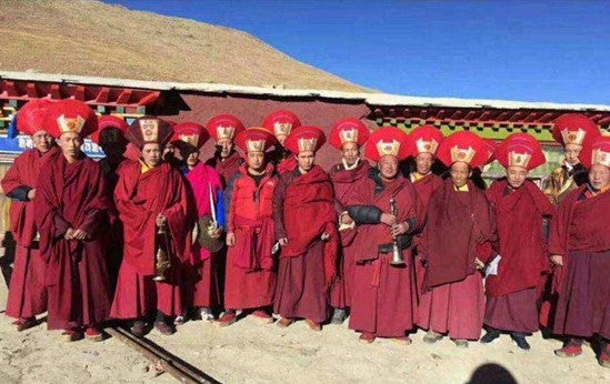 Monks wearing traditional red clothing and head gear.