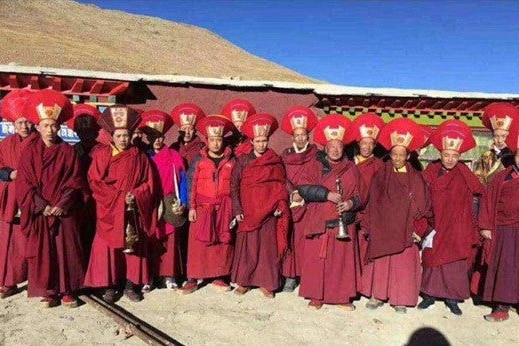 Monks wearing traditional red clothing and head gear.