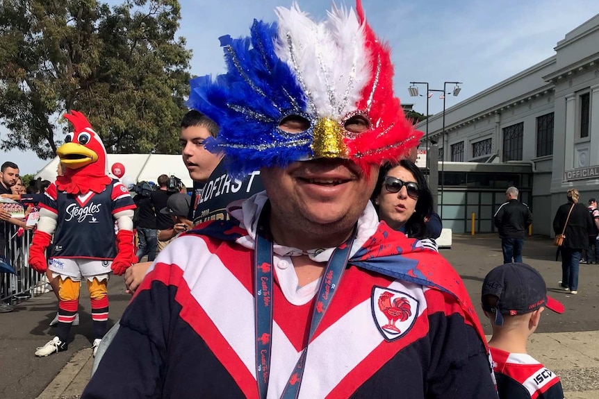 Man wearing red and white mask smiles