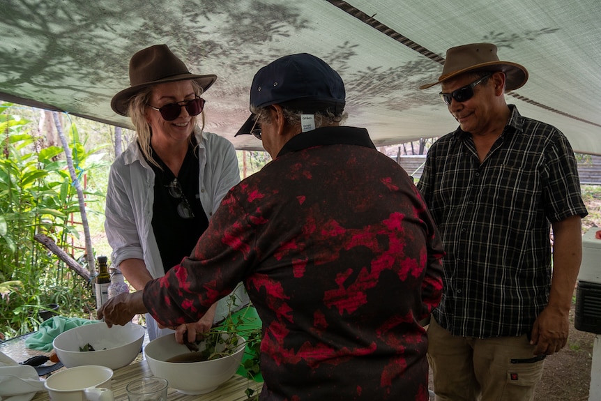 three people in bush kitchen preparing food