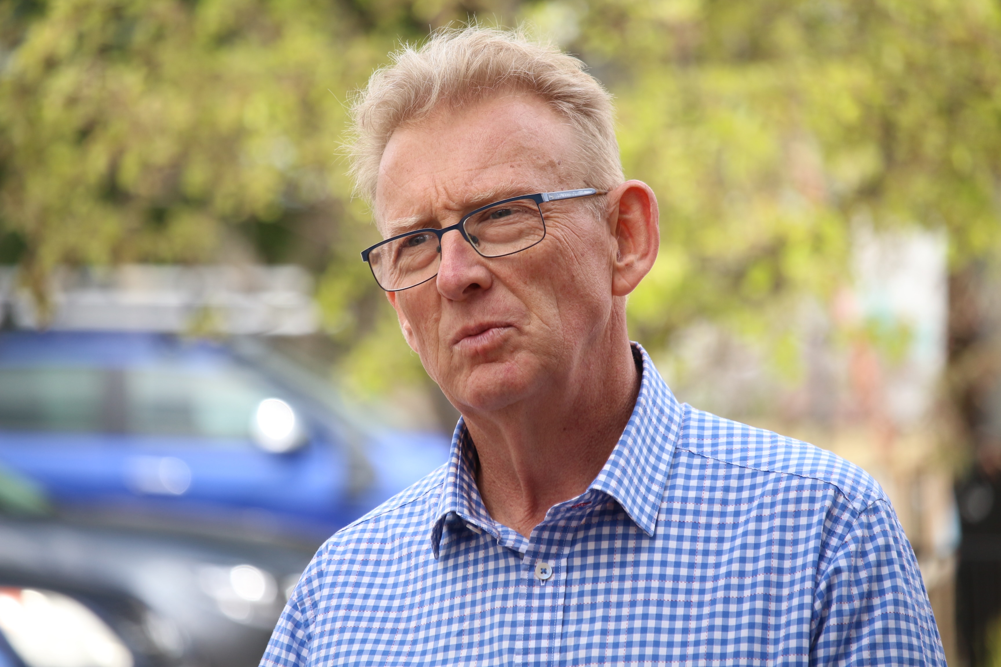 Un hombre con cabello rubio corto y gafas está afuera y parece un poco confundido.