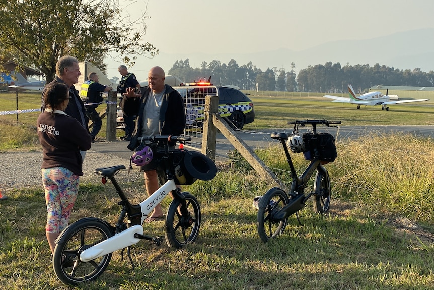 a group of people talk near an airport outside.