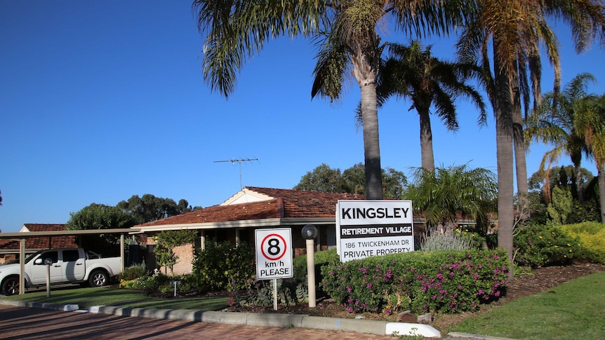 The exterior of Kingsley Retirement Village with shrubs and palm trees at the front of the property.