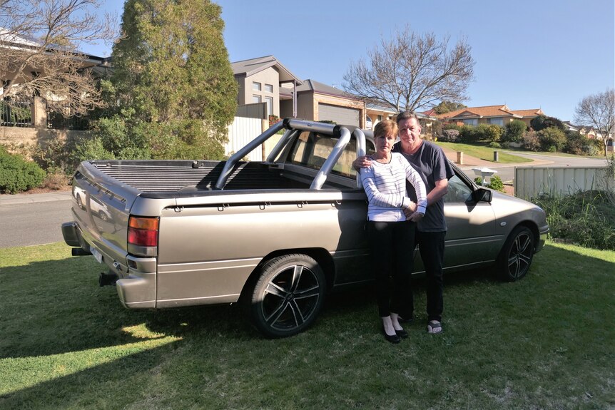 A woman and a man standing in front of a ute on a lawn