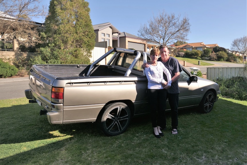 A woman and a man standing in front of a ute on a lawn