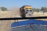 a view from the cab of a truck, passing a road train