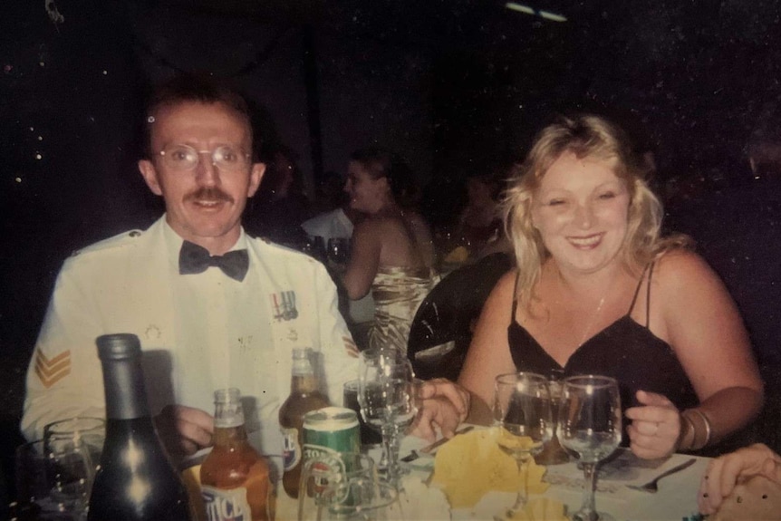 Man in white uniform and woman in black dress having dinner. Drinks on the table. Candid shot.