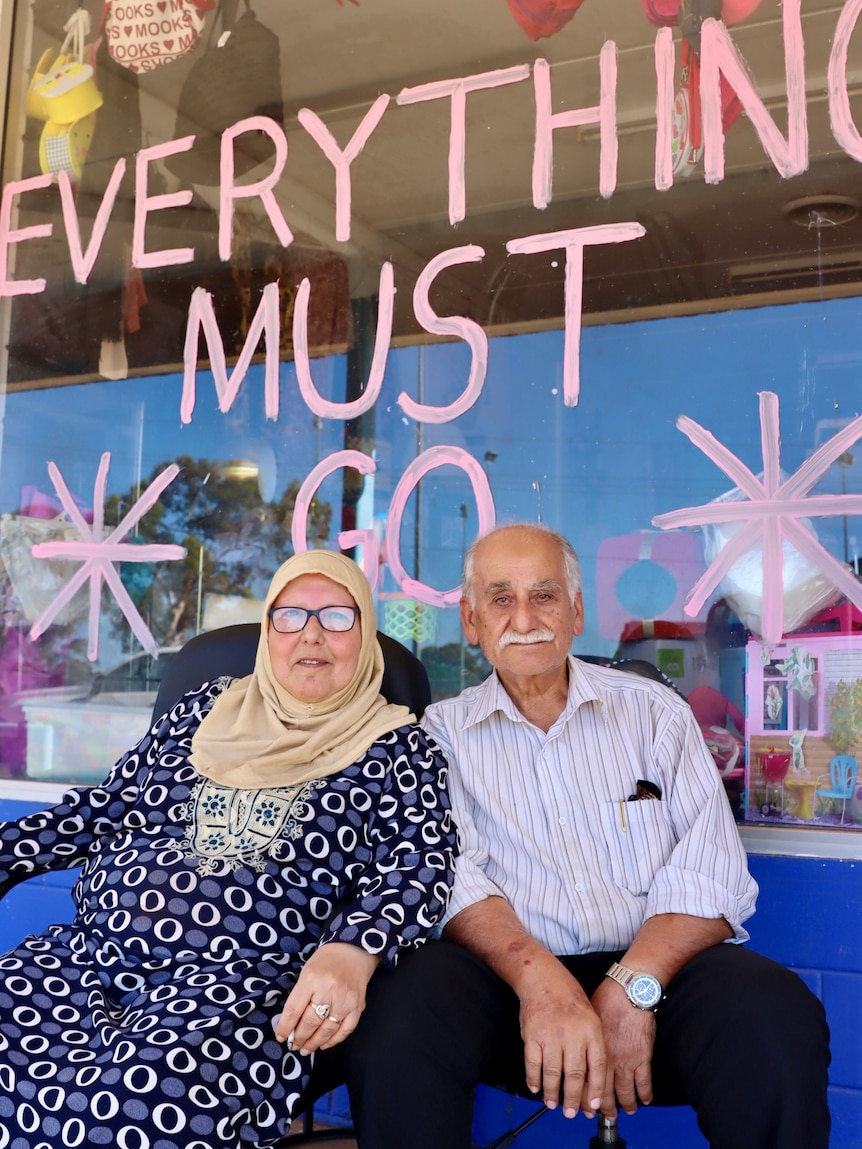 A man and a woman sit outside a video store in Kambalda.