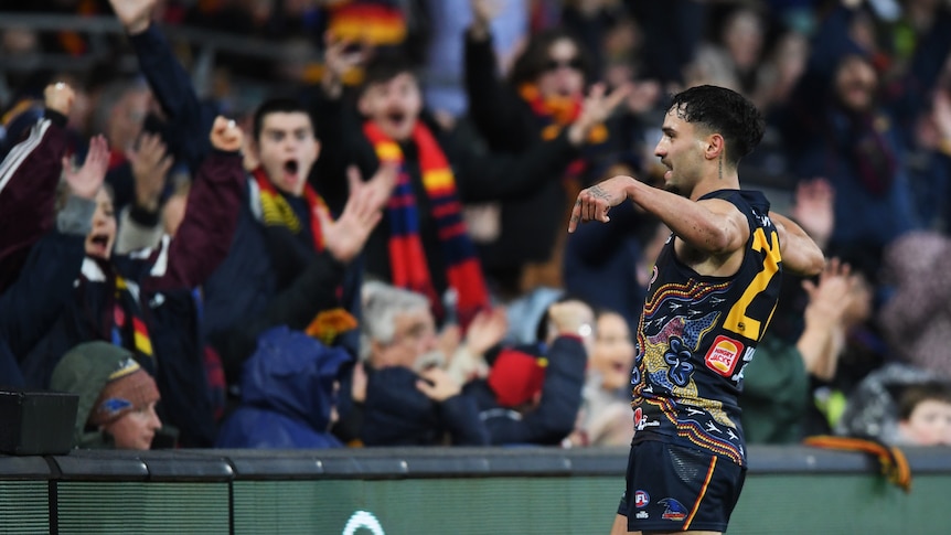 Izak Rankine points to the ground while facing the crowd, which is celebrating his goal