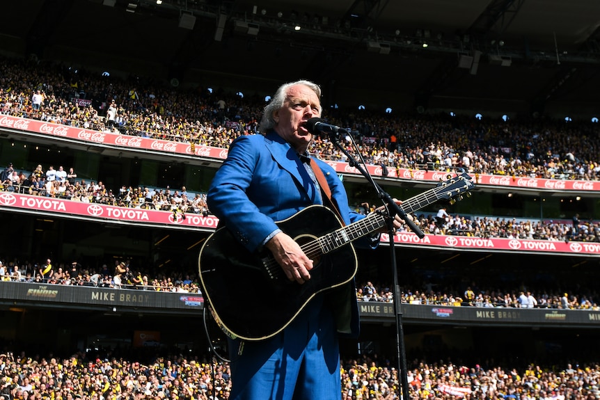 Mike Brady plays guitar and sings during pre-match entertainment at the MCG