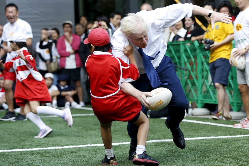 London Mayor Boris Johnson collides with 10-year-old Toki Sekiguchi during a Street Rugby match in Tokyo.