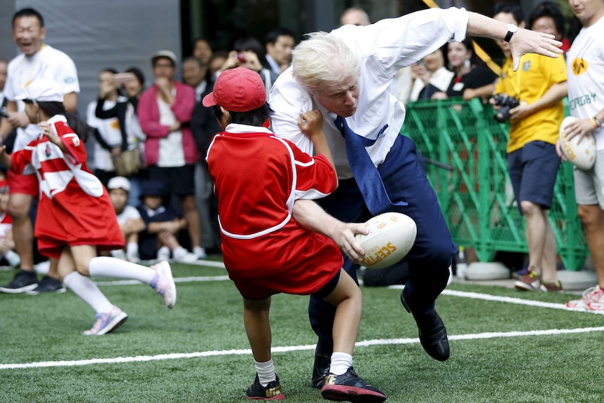 London's Mayor Boris Johnson collides with 10-year-old Toki Sekiguchi during a game of Street Rugby in Tokyo.