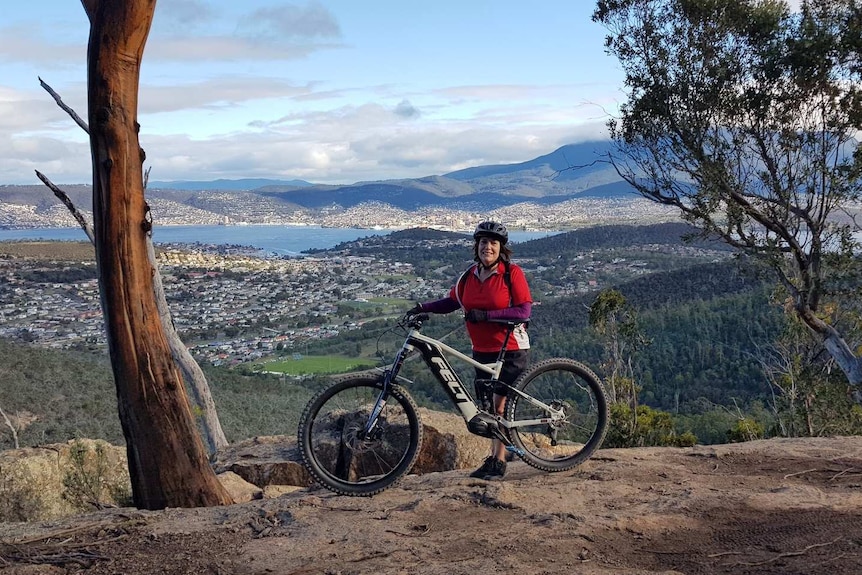 Michelle Quinn with her mountain bike on a hill overlooking Hobart.