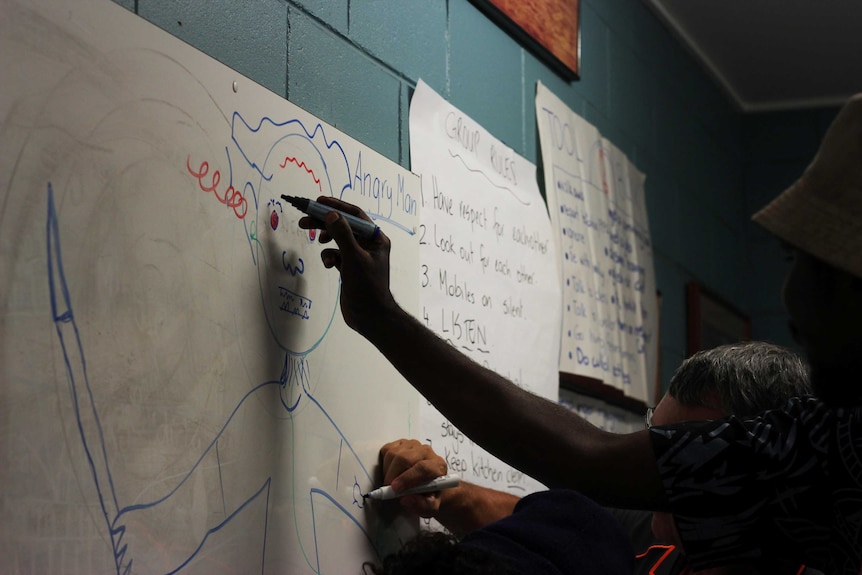 People taking part in a family violence workshop draw the sources of their anger on a whiteboard.