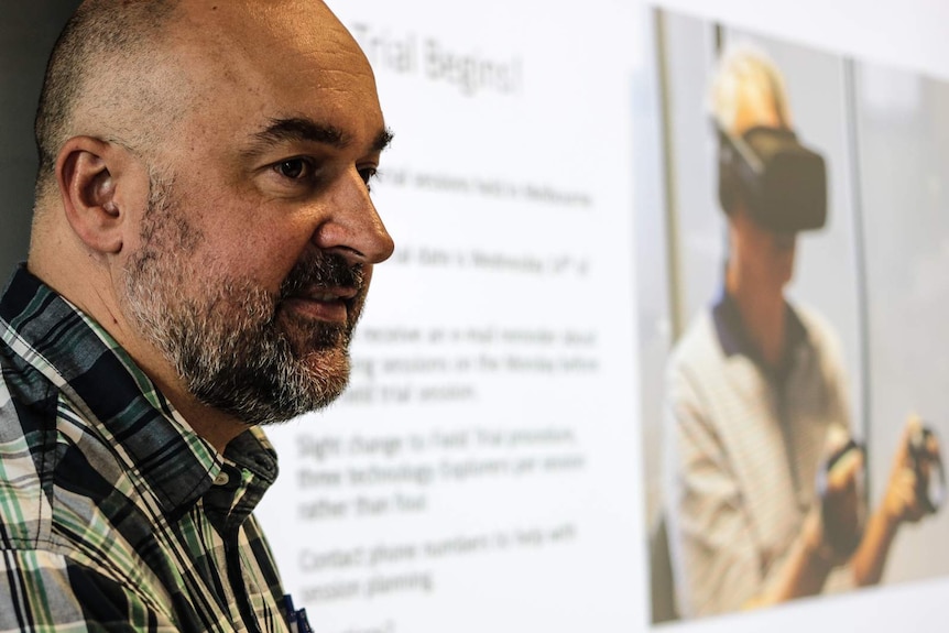 A man stands in front of a projected image displaying details of a virtual reality project