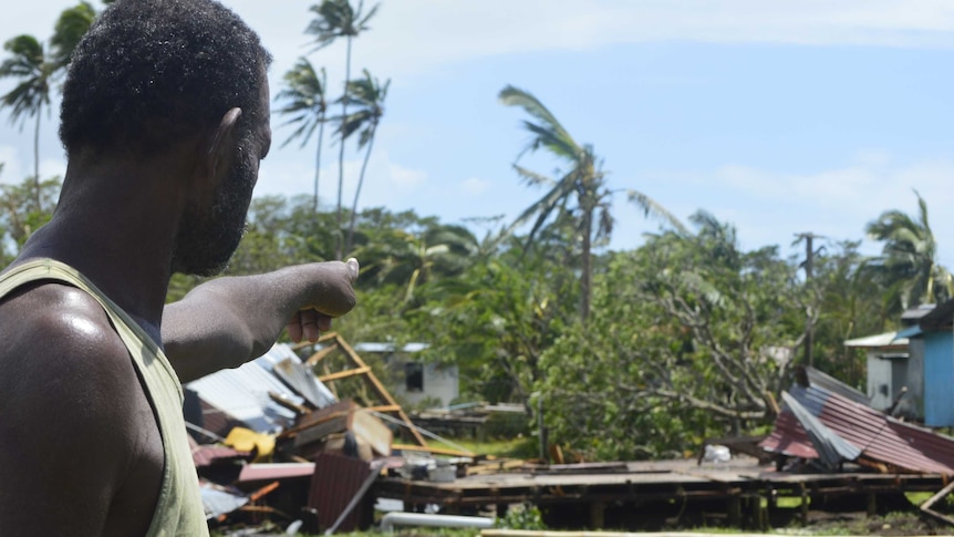 A man points to a house that has been destroyed by Tropical Cyclone Winston.