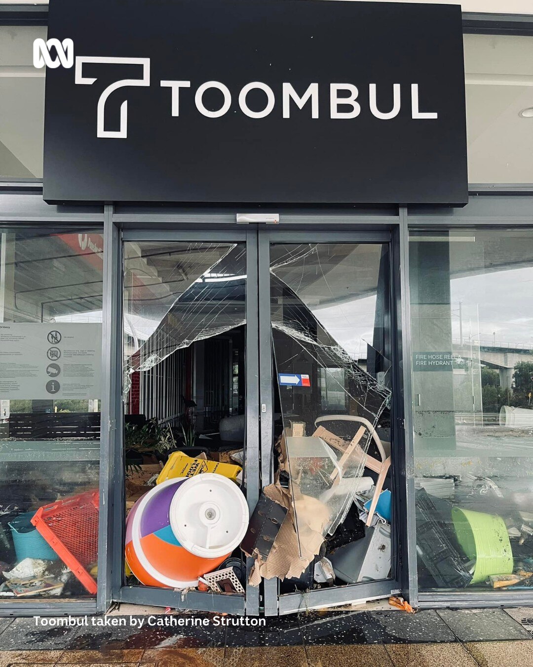 A shop front with goods strewn around it after a flood.