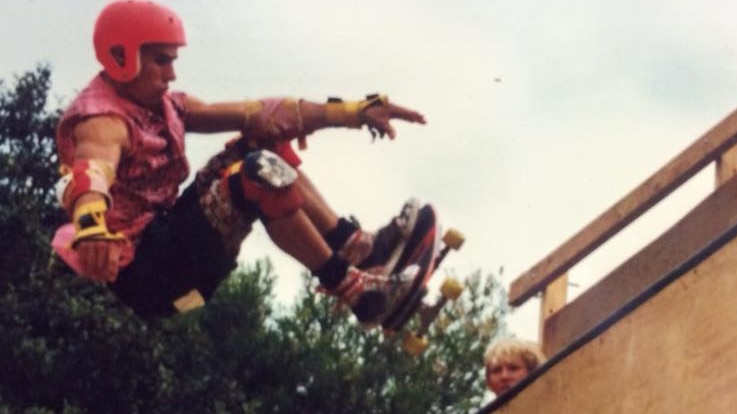 A man wearing a red helmet rides a skate board up a wooden ramp