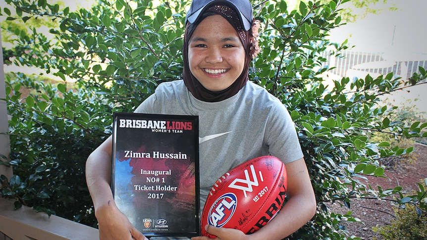Zimra Hussain hold a signed football and ticket plaque