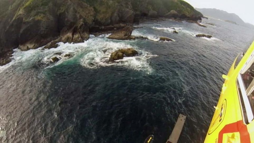 Tasmania's rescue helicopter flies along the coastline of Maatsuyker Island during the search for the deckhand.
