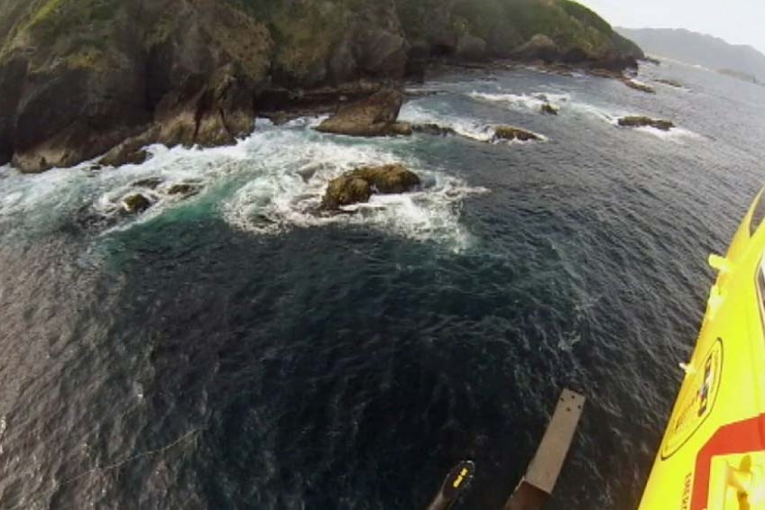 Tasmania's rescue helicopter flies along the coastline of Maatsuyker Island during the search for the deckhand.