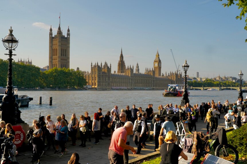 Queues of people line the River Thames at Lambeth. The Palace of Westminster is in the background.