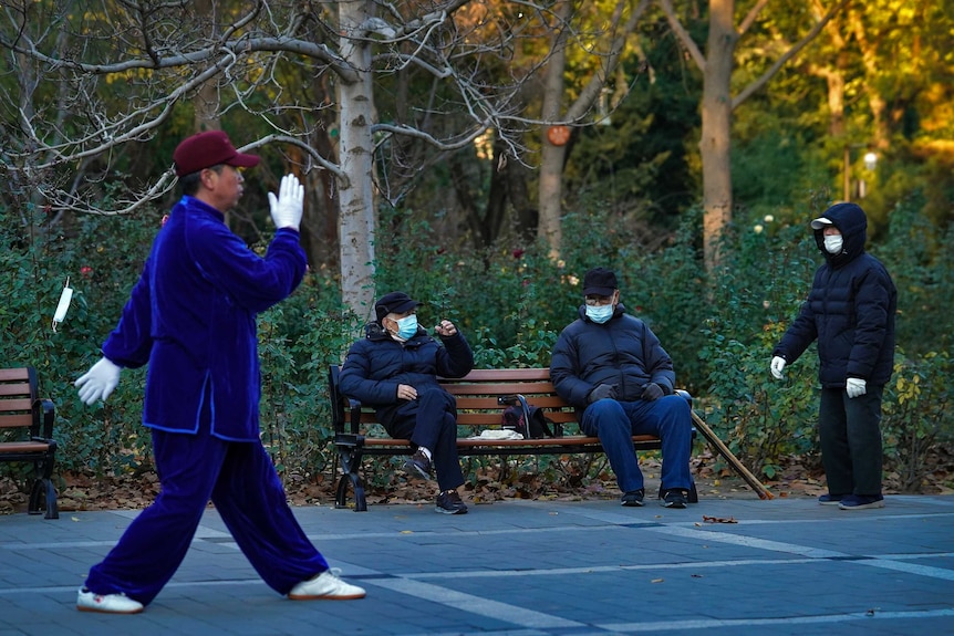 Elderly residents gather while wearing face masks in a Beijing park