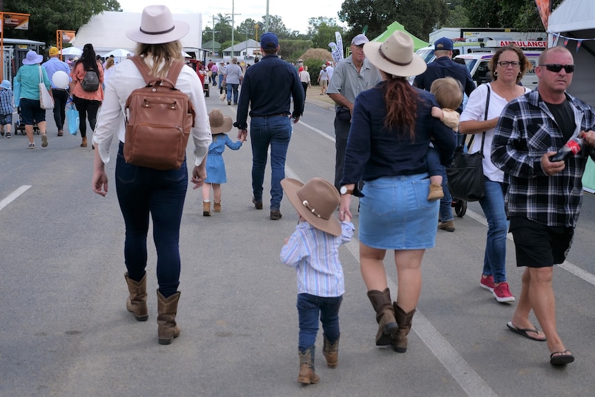 People wearing boots and hats walking around on a road.