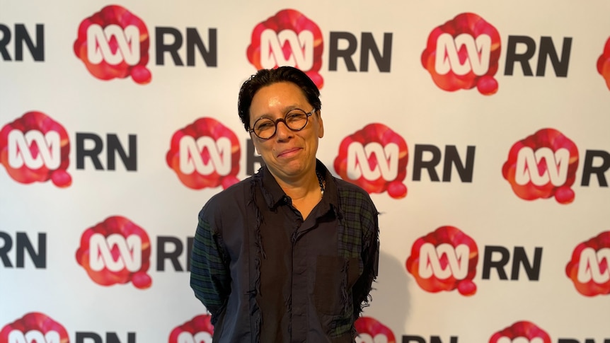 Person with glasses and a tassled black button down on half smiles against an RN Breakfast background