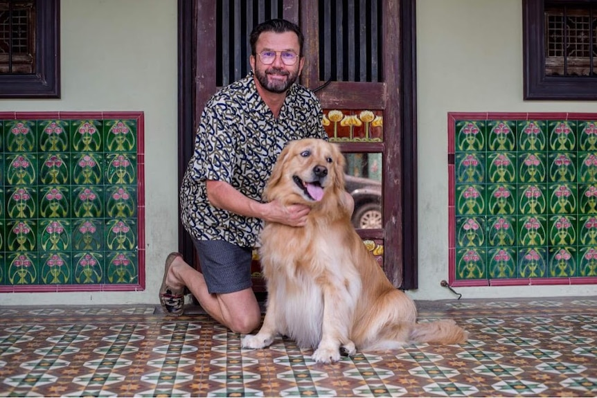 A man sitting on a floor with a dog next to him