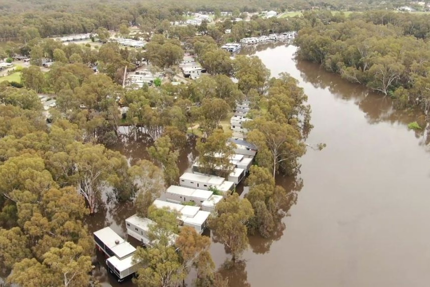 An aerial shot of houses on the edge of a swollen river.