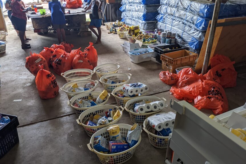 a concrete flood covered with washing baskets and bags full of food and toiletries 