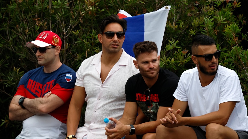 Four men stand in front of a Russian flag while in the crowd of a tennis match at the Australian Open.