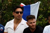 Four men stand in front of a Russian flag while in the crowd of a tennis match at the Australian Open.