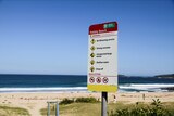 Image of a beach sign at beach on a sunny day. 