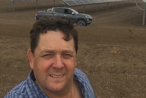 Cotton farmer Scott Morgan with the solar panels on his farm in the background.