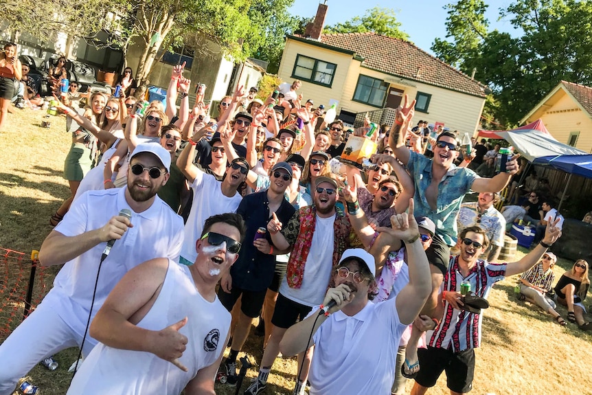 A picture showing a fifty young women and men in the backyard of a Melbourne home celebrating with beverages and music