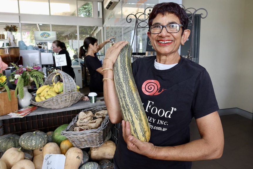 A woman with a huge zucchini.