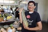 A woman with a huge zucchini.