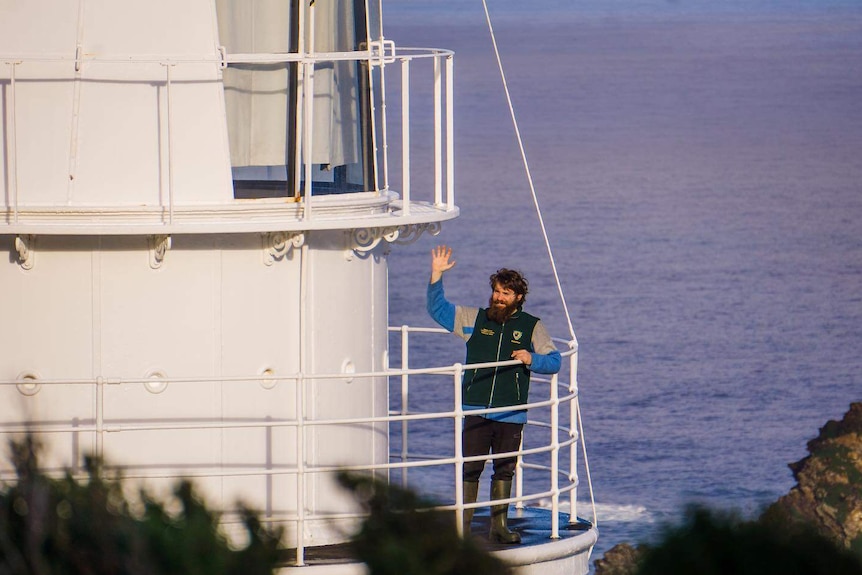A man on a lighthouse waving