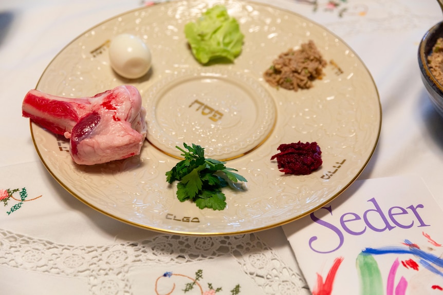 A plate holds six ritual foods: a shank bone, egg, bitter herb, a sweet nut paste, horseradish and lettuce.