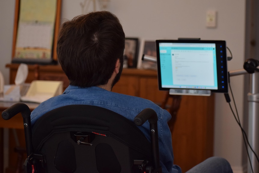 Image from behind of a man looking at a computer screen. 