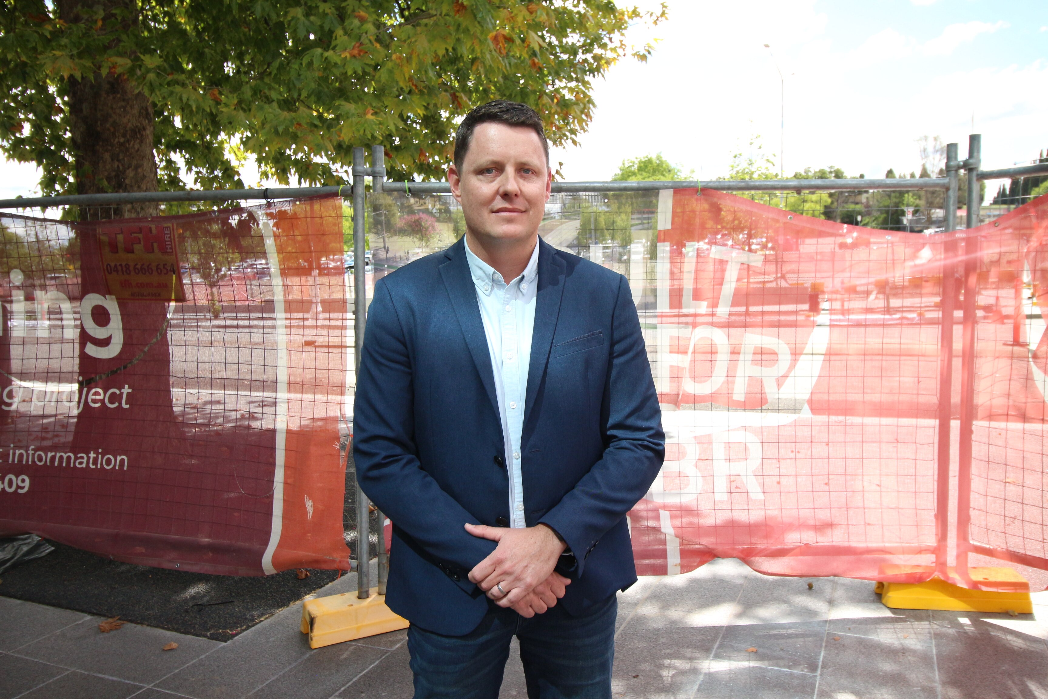 Un hombre con un traje de la Armada se encuentra frente a un área de construcción cercada.